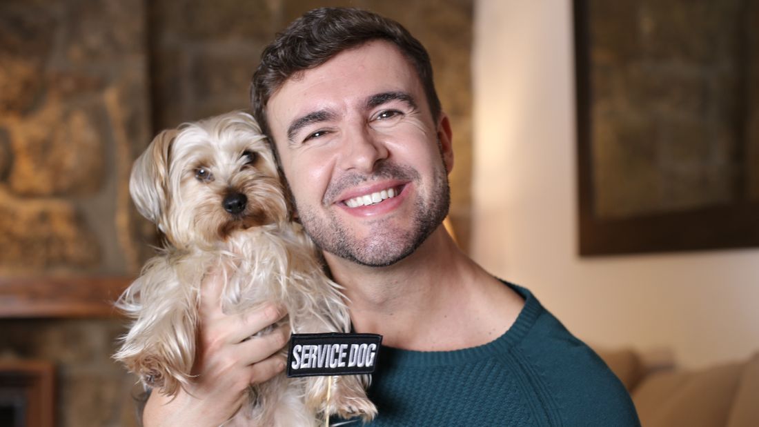 A man holding a small dog, smiling
