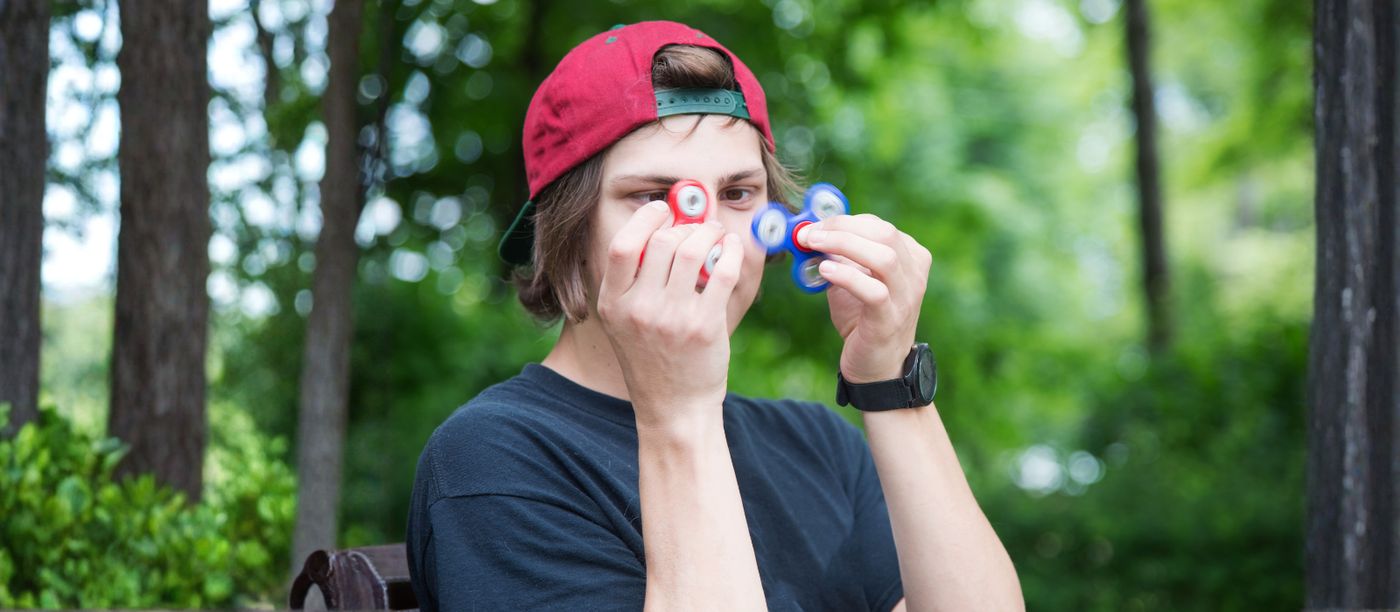 A person outdoors holding a fidget toy, relaxed