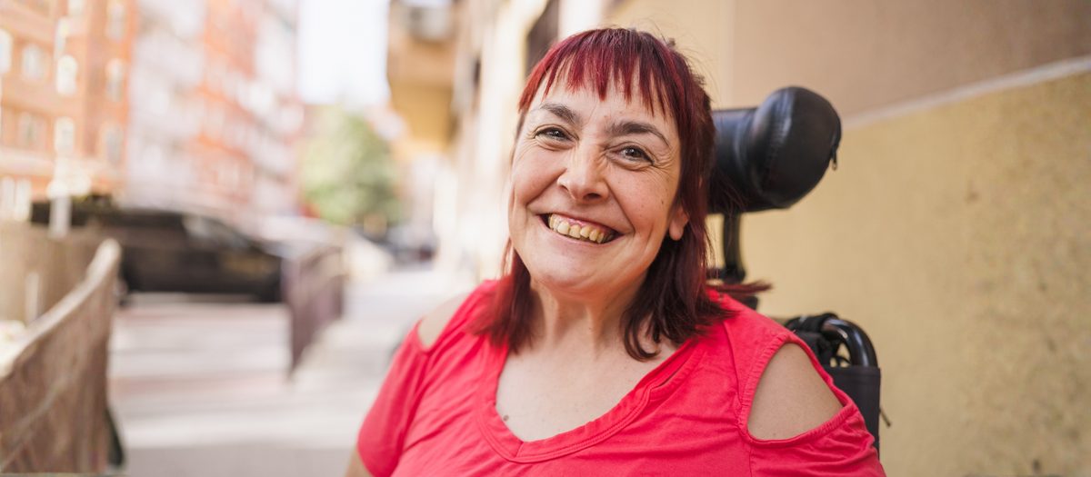 A woman in a red top smiling, out on a city street